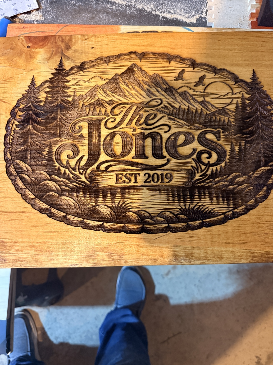 The Jones family wooden sign with mountain, forest, lake, and sunset scenery, established 2019